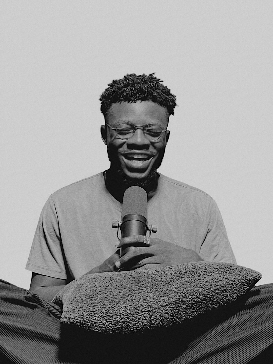 Kash smiling, holding a studio microphone